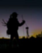 Photograph of a hunter on hunting land in front of a sunset